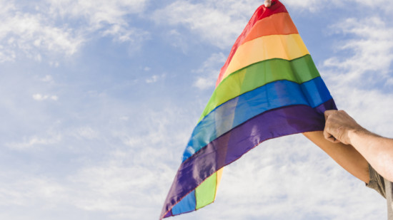 Mann mit Regenbogenfarben vor Himmel
